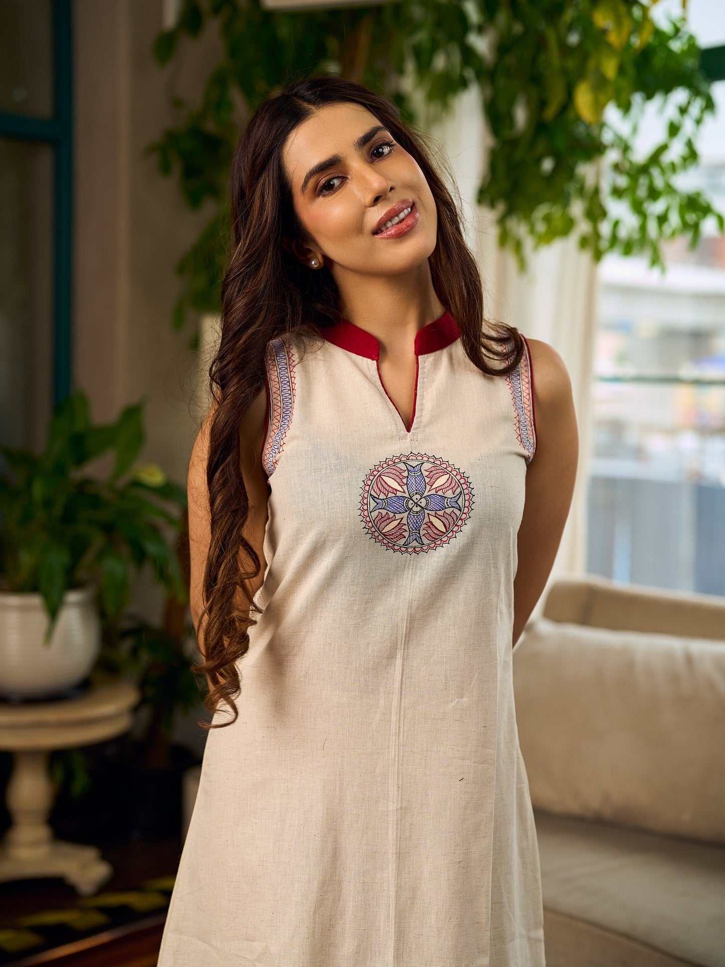 Off-white dress featuring intricate Madhubani artwork and a maroon Mandarin collar.