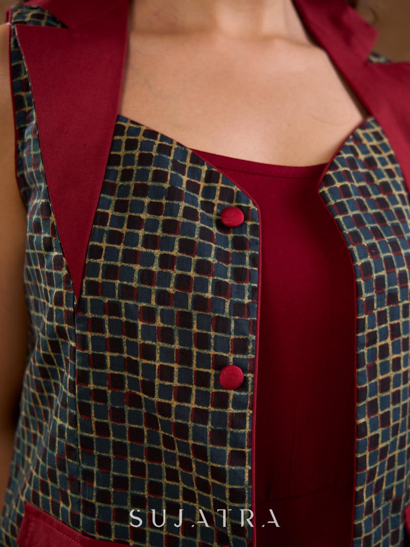 Sharp dark teal and maroon checkered sleeveless jacket with a distinctive notch collar and princess-cut tailoring, offering a structured silhouette ideal for elevated corporate styling.