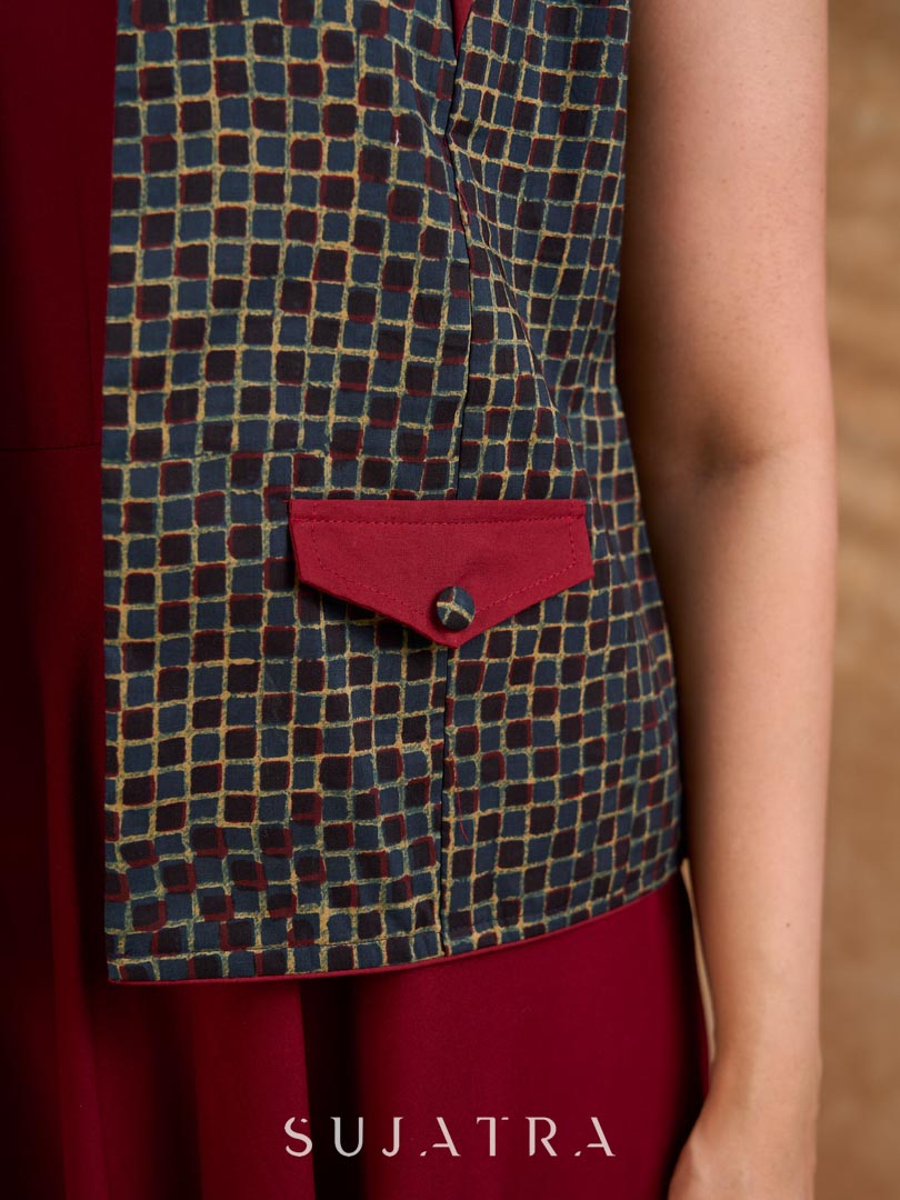 Sharp dark teal and maroon checkered sleeveless jacket with a distinctive notch collar and princess-cut tailoring, offering a structured silhouette ideal for elevated corporate styling.