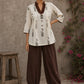 Off-white floral printed top with brown ruffled collar, button front, tie-up sleeves, tassel details, and contrast accents.