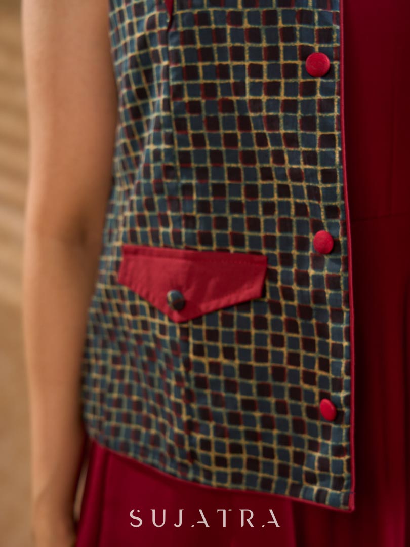 Sharp dark teal and maroon checkered sleeveless jacket with a distinctive notch collar and princess-cut tailoring, offering a structured silhouette ideal for elevated corporate styling.