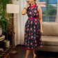 Elegant black Kalamkari dress featuring blooming florals and contrasting pink detailing for refined charm.