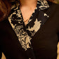 Chic black overlapping blazer-style wrap dress featuring printed black-and-white collar, cuffs, tie detail, and subtle accents