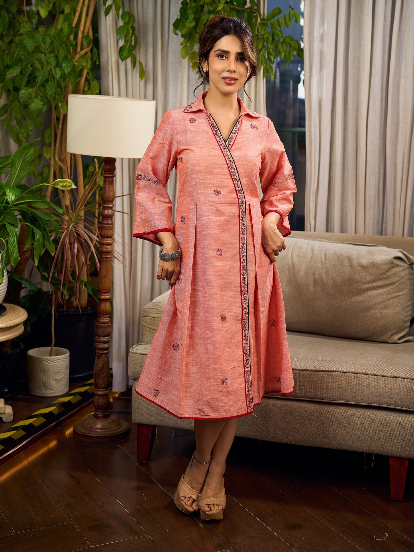 Peach dress featuring delicate Madhubani painting and graceful flared sleeves.