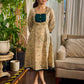 Artisanal beige Madhubani dress featuring intricate motifs, a contrasting green yoke, and refined accents.