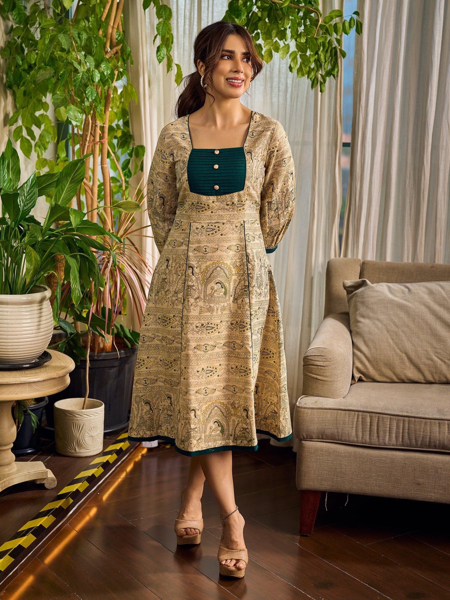 Artisanal beige Madhubani dress featuring intricate motifs, a contrasting green yoke, and refined accents.