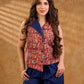 Sharp sleeveless red Kalamkari overlap jacket with a statement one-sided flap, Chinese collar, and navy accents, offering a clean, structured silhouette ideal for elevated corporate styling.