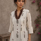 Off-white floral printed top with brown ruffled collar, button front, tie-up sleeves, tassel details, and contrast accents.