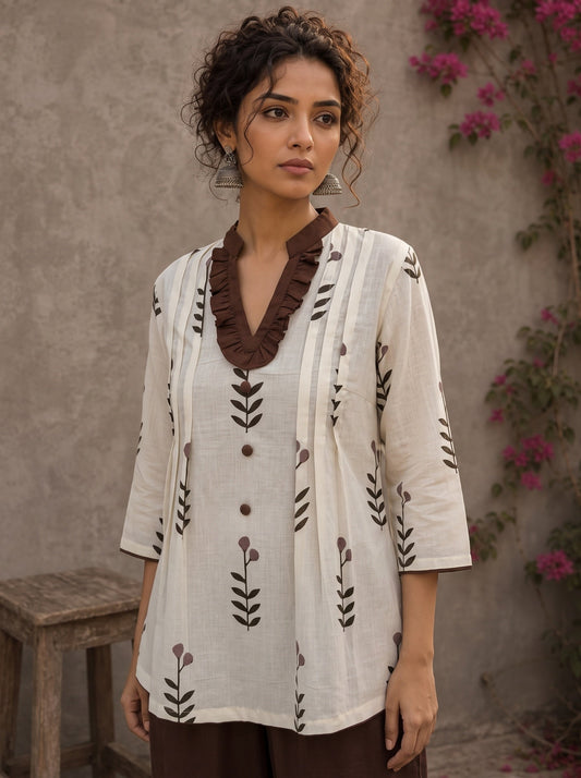Off-white floral printed top with brown ruffled collar, button front, tie-up sleeves, tassel details, and contrast accents.