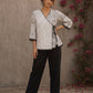 Black and white printed crossover top with contrast polka dots, lace-trimmed sleeves, side tie, tassels, and scalloped hem.