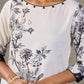 White and black floral dress with pearl embellishments and black accents.