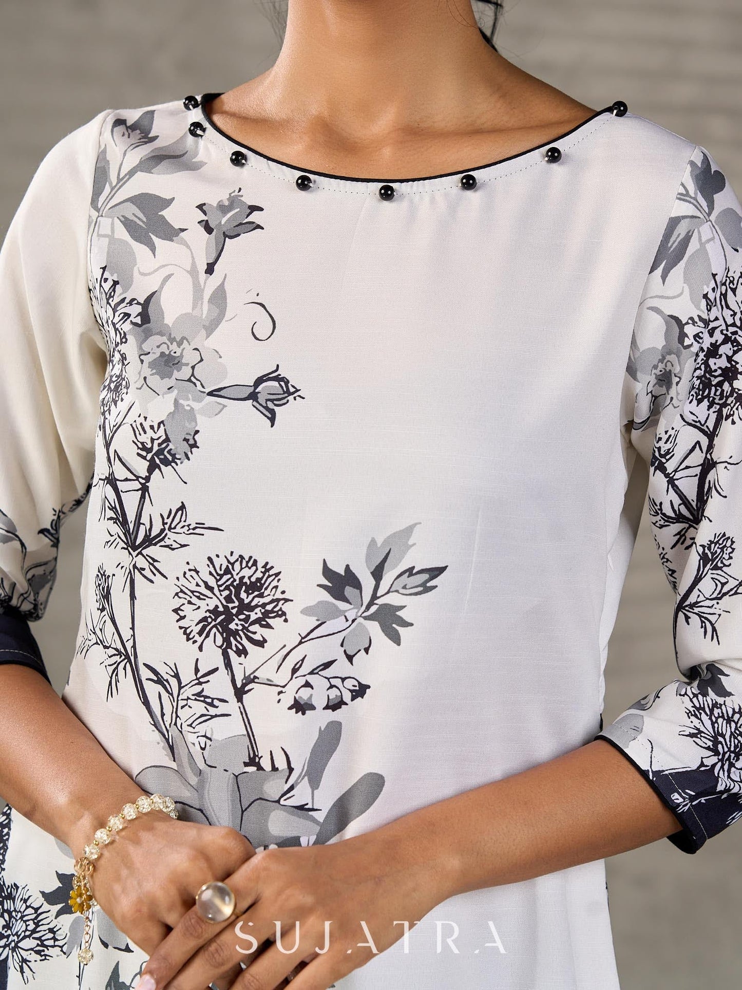 White and black floral dress with pearl embellishments and black accents.