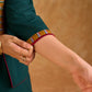 Sophisticated bottle green and mustard Ikat jacket featuring an overlapping neckline closure, front-open design, and rich maroon accents, offering a composed, tailored silhouette for corporate wear.