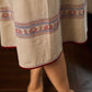 Off-white dress featuring intricate Madhubani artwork and a maroon Mandarin collar.