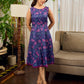 Enchanting purple panel dress featuring vibrant magenta floral prints, a sleeveless silhouette, and a graceful fit-and-flare design for timeless elegance.