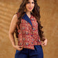 Sharp sleeveless red Kalamkari overlap jacket with a statement one-sided flap, Chinese collar, and navy accents, offering a clean, structured silhouette ideal for elevated corporate styling.