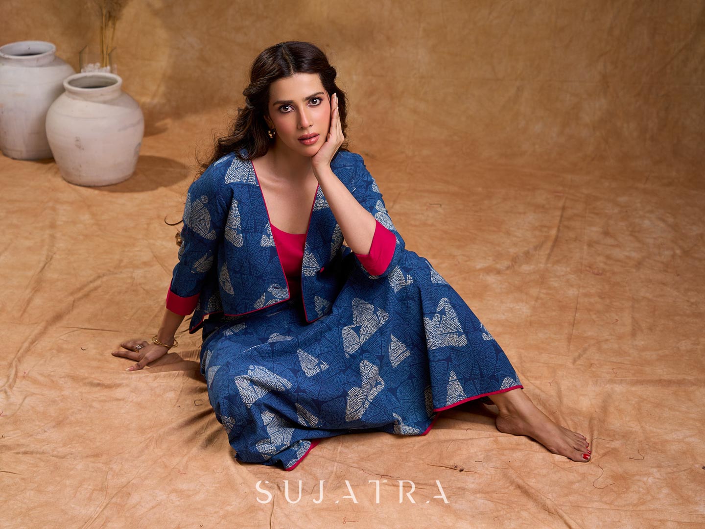 Deep indigo jacket with an asymmetric front closure, magenta folded cuffs, and coordinated accents, offering a structured silhouette with bold contrast and a refined look for elevated corporate styling.