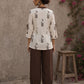 Off-white floral printed top with brown ruffled collar, button front, tie-up sleeves, tassel details, and contrast accents.