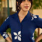Navy blue apple-cut shirt dress with white floral hand block motifs, conceptually placed and finished with clean white edging and red accents for a refined, contemporary look.