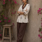 Off-white floral printed top with brown ruffled collar, button front, tie-up sleeves, tassel details, and contrast accents.