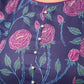 Enchanting purple panel dress featuring vibrant magenta floral prints, a sleeveless silhouette, and a graceful fit-and-flare design for timeless elegance.
