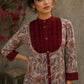 Elegant maroon floral top with intricate maroon pleats, high neckline, covered buttons, and coordinating sleeve cuffs.