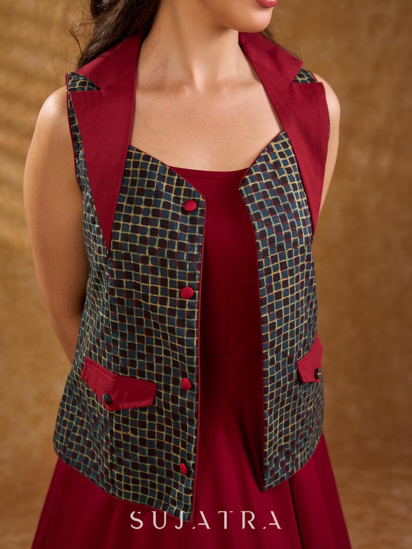 Sharp dark teal and maroon checkered sleeveless jacket with a distinctive notch collar and princess-cut tailoring, offering a structured silhouette ideal for elevated corporate styling.