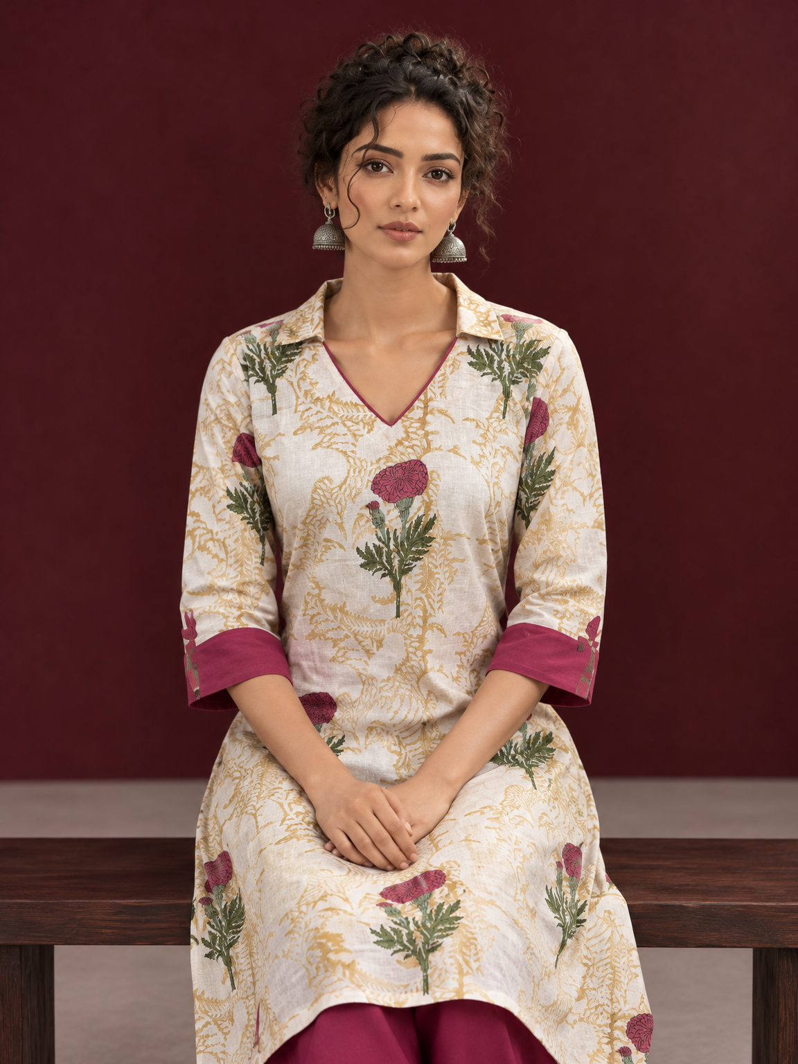 Ivory floral printed kurta with pink and green flowers, a V-neck, and contrasting pink cuffs. — seated detail