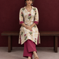 Ivory floral printed kurta with pink and green flowers, a V-neck, and contrasting pink cuffs. — seated