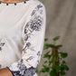 White and black floral dress with pearl embellishments and black accents.