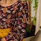 Mustard Kalamkari dress with an asymmetrical yoke and puffed sleeves.