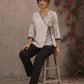 Black and white printed crossover top with contrast polka dots, lace-trimmed sleeves, side tie, tassels, and scalloped hem.