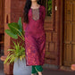 Exquisite deep burgundy printed kurta with intricate neck panel embroidery, delicate green beads, and refined green highlights.