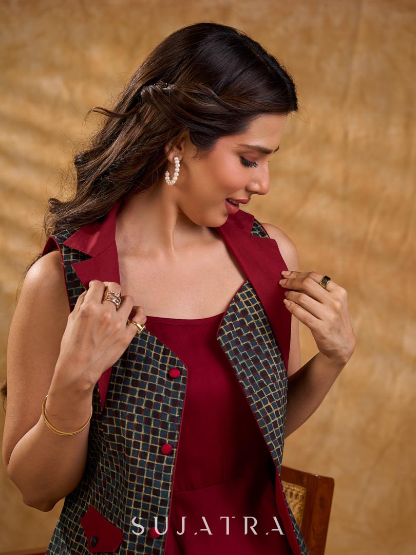 Sharp dark teal and maroon checkered sleeveless jacket with a distinctive notch collar and princess-cut tailoring, offering a structured silhouette ideal for elevated corporate styling.
