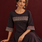 Elegant Black Ajrakh Polka Dot Printed Dress with Maroon Ajrakh Floral Border Yoke and Matching Sleeve Cuffs — seated detail