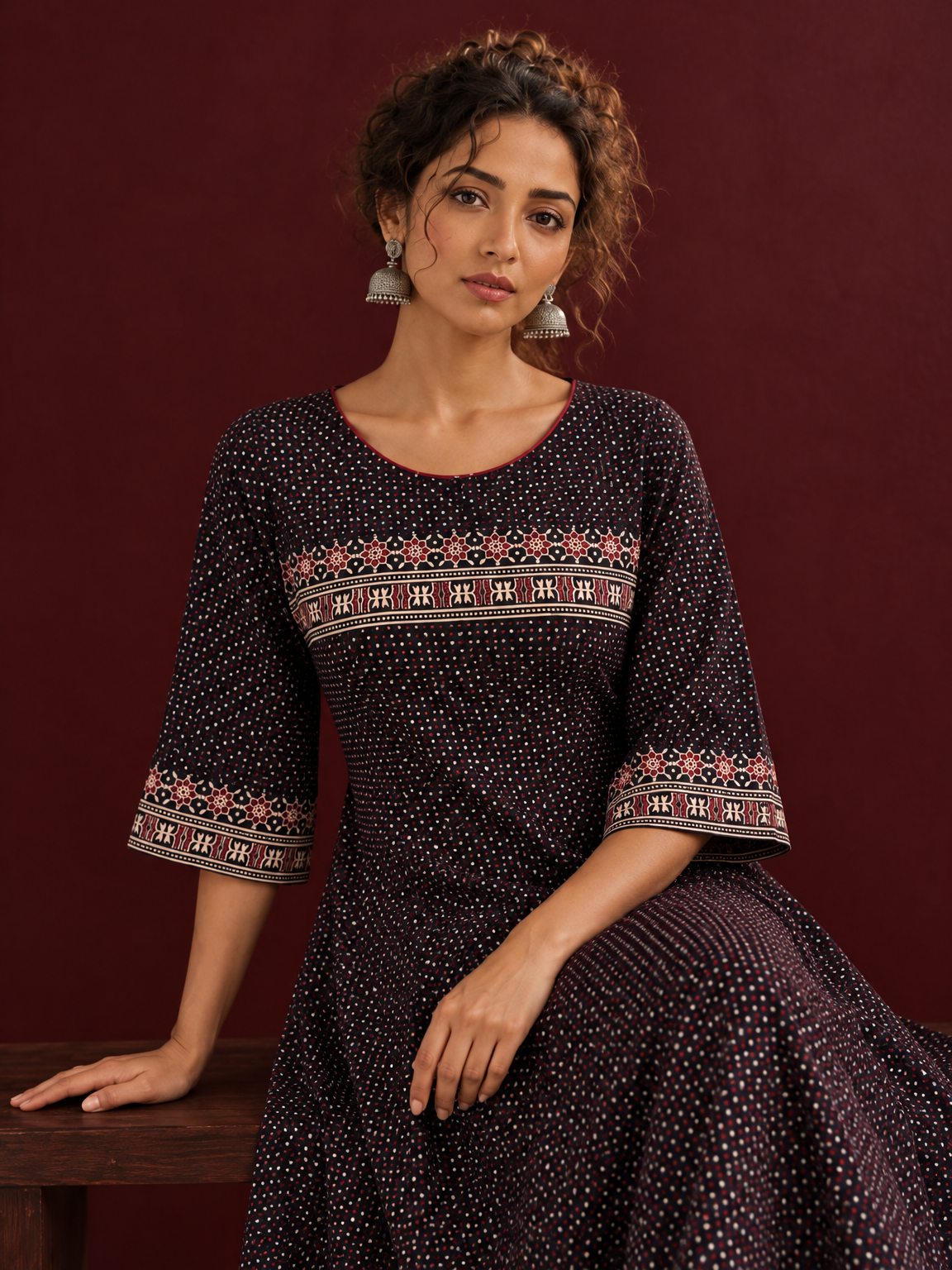 Elegant Black Ajrakh Polka Dot Printed Dress with Maroon Ajrakh Floral Border Yoke and Matching Sleeve Cuffs — seated detail