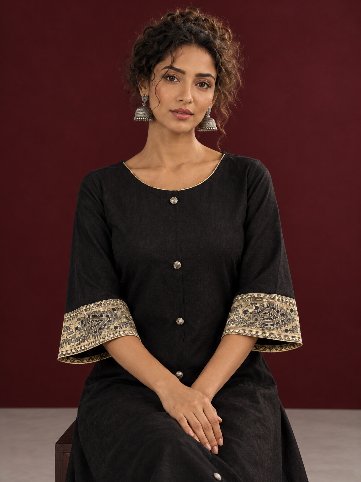 Elegant Black Cotton A-Line Dress with Madhubani Print Border Hem and Matching Bell Sleeve Cuffs — seated detail