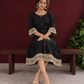 Elegant Black Cotton A-Line Dress with Madhubani Print Border Hem and Matching Bell Sleeve Cuffs — seated