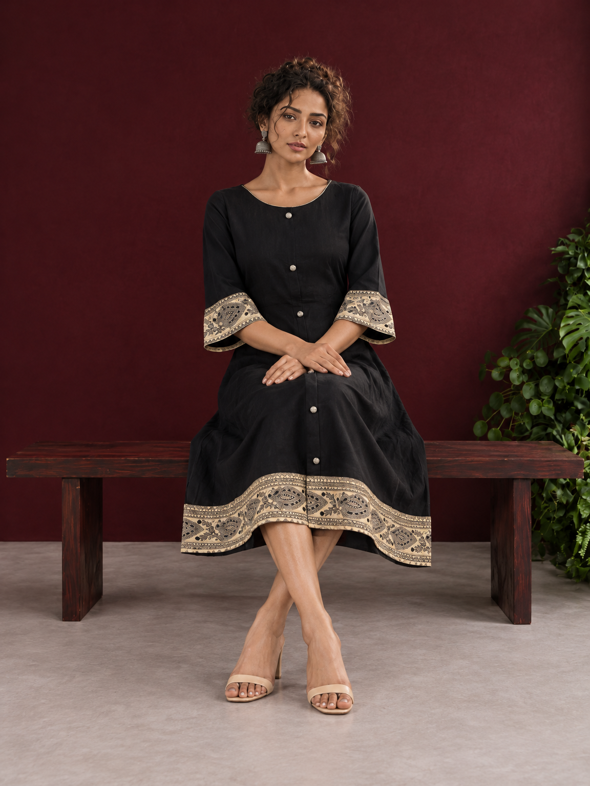 Elegant Black Cotton A-Line Dress with Madhubani Print Border Hem and Matching Bell Sleeve Cuffs — seated