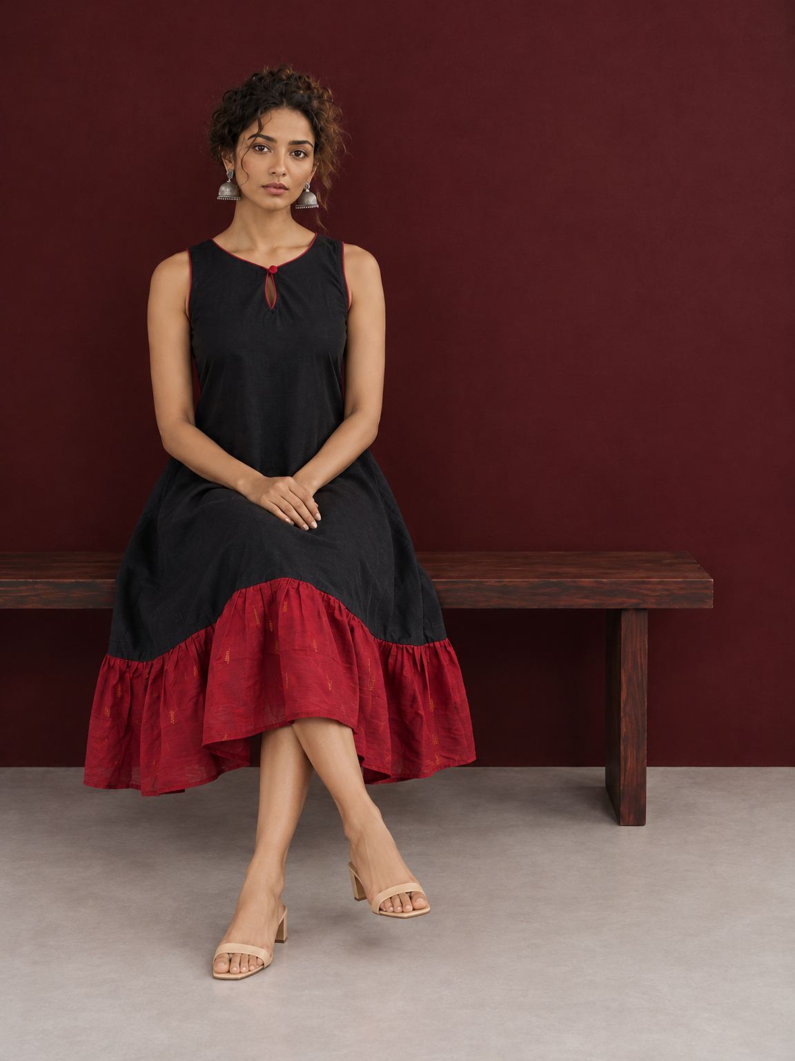Classic Black Cotton Silk Dress with Keyhole Neckline and Contrast Maroon Ruffle Hem — seated